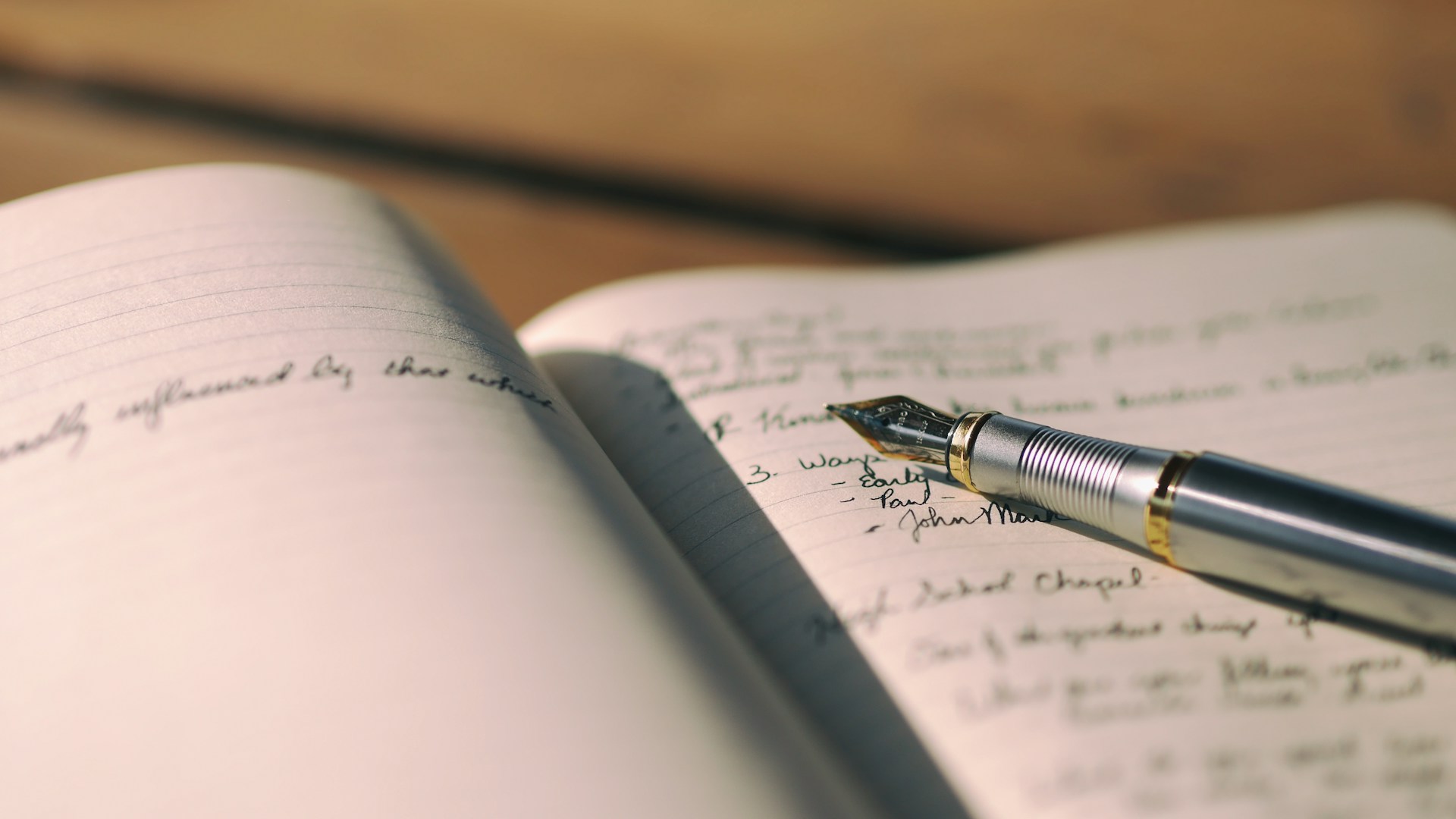 Motivos de compra: caderno aberto com notas escritas à mão e uma caneta de aparo pousada nas linhas
